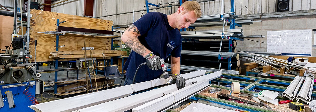 A Martindales fabricator assembling a white window frame in its manufacturing workshop